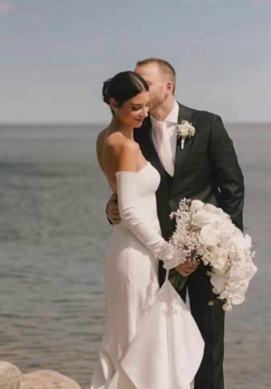 Couple on a beach holding a bouquet of flowers